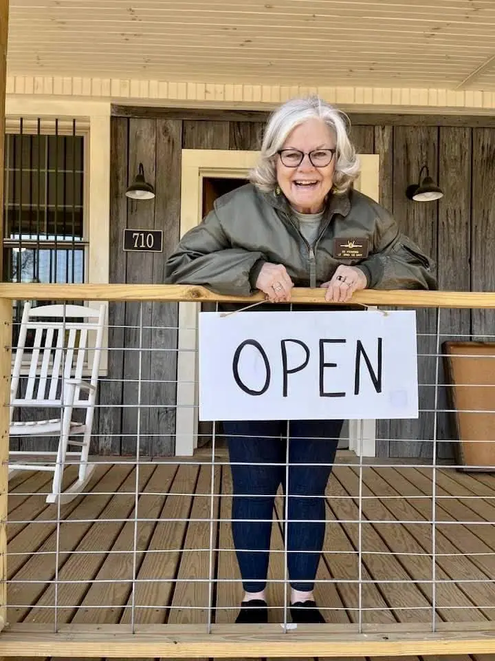 Owner of The Olde Store at Grassy Creek holding OPEN sign